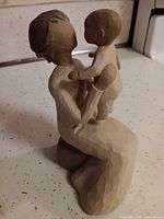 Front view of kneeling grandmother figurine holding child