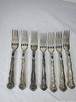 Seven silver-plated forks front view on cloth background