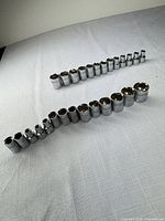 Two rows of chrome sockets ordered by size on cloth surface