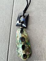 Front view of abalone shell pendant with hematite rectangle and glass bead on cord