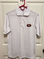 Full front view of white Antigua polo with 49ers logo