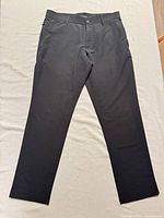Full view of black slim chino pants laid flat