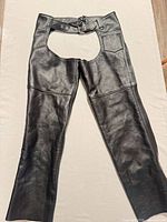 Full view of black leather motorcycle chaps showing belt, pocket, leg seams