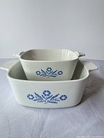 Two nested white CorningWare casseroles showing blue Cornflower motif