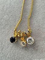 Close-up of three pendants on gold tone chain
