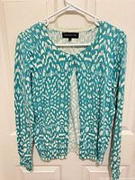 Front view of teal and white ikat cardigan on hanger
