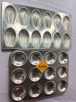 Three madeleine pans stacked with bun pan below showing cavities