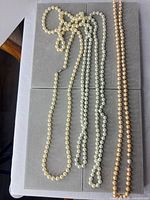 All three pearl necklaces laid out to show lengths and colour variations