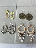 All four pairs of earrings laid out on gray surface