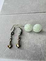 Both earring pairs laid out on grey surface showing styles, colours and closures