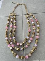 Full view of three-strand necklace laid flat showing beads and extender