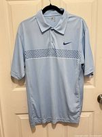 Front view of Nike light blue Dri-FIT polo shirt on hanger
