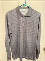 Front view of gray Nike Golf long-sleeve polo on hanger