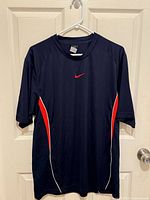 Front view of Nike navy running shirt with red side panels and white piping
