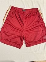 Front view of red Nike mesh basketball shorts showing side stripes, swoosh logo, and S emblem