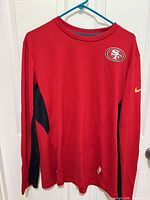 Front view showing 49ers logo, red body, black side panels, Nike swoosh