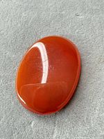 Front view of oval orange-red cabochon gemstone