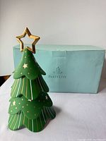 Front view of green ceramic Christmas tree candle holder with gold accents and box