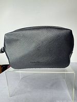 Front view of black Saffiano leather toiletry bag with embossed logo