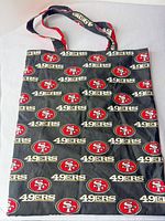Full view of the San Francisco 49ers logo cotton canvas tote bag showing pattern and straps
