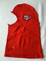 Front view of red fleece balaclava showing overall shape and logos