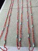 Three red glass bead necklaces laid out to show full length and bead pattern
