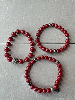 All three red beaded stretch bracelets laid flat