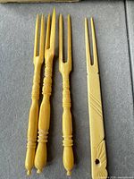 Four yellow carving forks laid out on grey background