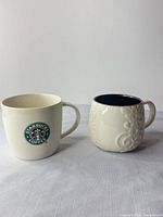 Front view of both Starbucks mugs showing exterior designs and handles