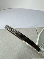 Side view showing braided pattern and tarnish on sterling bangle