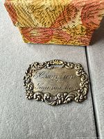 Front view of engraved sterling silver plaque beside fabric box