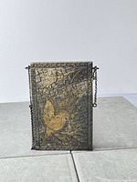 Front view showing full engraved bird and floral design, chain at side