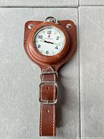 Full view of pocket watch in leather holder with strap