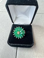 Ring in presentation box showing floral green stone design
