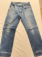 Full front view of faded light blue Wrangler jeans laid flat