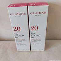 Front view of both Clarins Lip Comfort Oil boxes