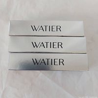 Three silver Lise Watier boxes stacked front logo visible