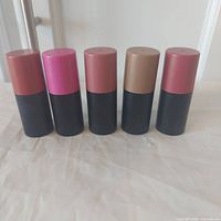 Five blush sticks standing upright showing colored caps