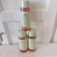 Front view of three sealed Pixi Glow Tonic 100 ml bottles