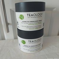 Front view of two stacked Teaology Jasmine Tea Firming Body Cream jars