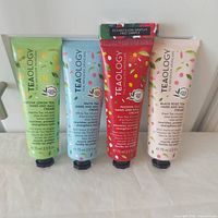 Front view of four Teaology hand & nail cream tubes and fragrance sample