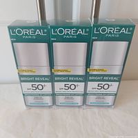 Front view of three boxed L'Oreal Bright Reveal SPF 50+ lotions