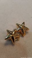 Front view of both star earrings showing gold-tone finish and crystal insets
