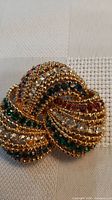 Front view of gold-tone rhinestone knot brooch showing multicoloured stones