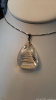 Front view of glass teardrop pendant on display bust
