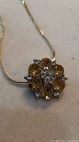 Necklace pendant close-up showing yellow stones and rhinestones