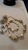 Full set showing gold-tone necklace, bracelet, cluster earrings and silver-tone earrings