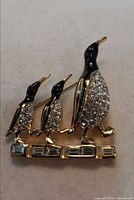 Front view of gold-tone three-penguin crystal brooch