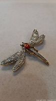 Full view of dragonfly brooch showing crystal wings and red heart