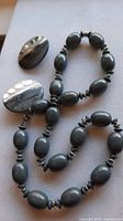 Necklace coiled beside both earrings showing overall style